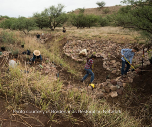 A rock crew, Community Weavers, building erosion control structures to restore a degraded landscape.